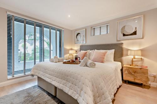 - une chambre avec un grand lit blanc et des fenêtres dans l'établissement High Tides Elegant & Modern 4-Bedroom Villa in Sandbanks, à Sandbanks