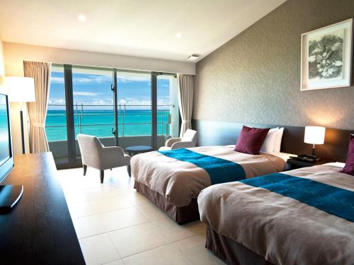a hotel room with two beds and a view of the ocean at Hotel Hamahigashima Resort in Uruma