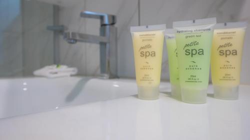 three bottles of sunscreen sitting on a counter in a bathroom at Hampton Court Apartments in Brisbane