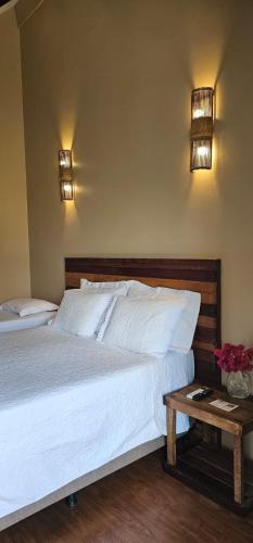 a bedroom with a large white bed and a table at Pousada Pedra Grande in Serra de São Bento