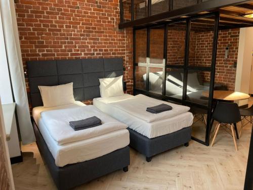 two beds in a room with a brick wall at Pod Błękitnymi Podkowami in Wrocław