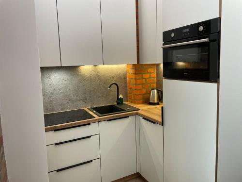 a white kitchen with a sink and a microwave at Pod Błękitnymi Podkowami in Wrocław