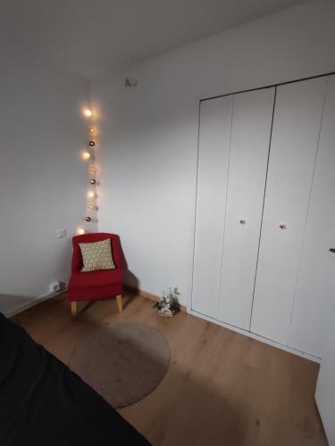 a room with a red chair and a white cabinet at appartement dans maison de village in Pinet