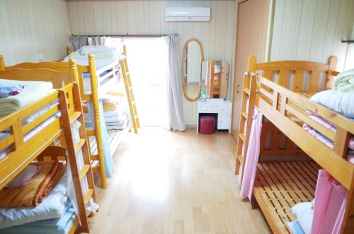 a dorm room with several bunk beds and a hallway at Goto Guest House Utojuku in Goto