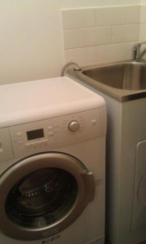 a washing machine in a bathroom with a sink at Annies Garden Cottage in Hobart