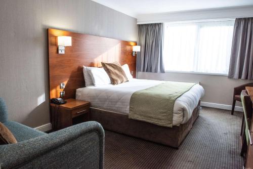 a hotel room with a bed and a chair at Holiday Inn Newcastle South by IHG in Boldon