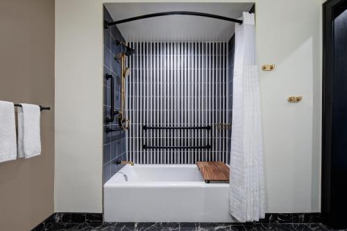 a white bath tub in a bathroom with a shower at The LaSalle Hotel, Bryan College Station, a Tribute Portfolio Hotel in Bryan
