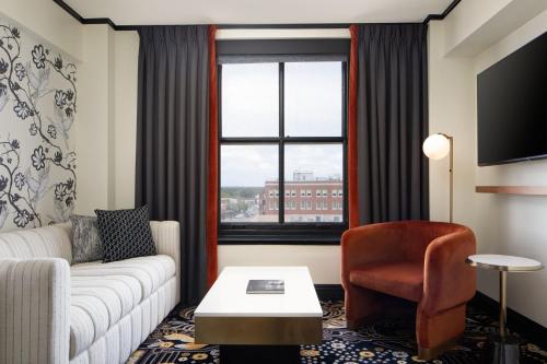 a living room with a couch and a chair and a window at The LaSalle Hotel, Bryan College Station, a Tribute Portfolio Hotel in Bryan