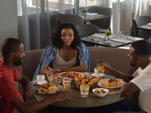 a group of people sitting around a table eating food at Novotel Lubumbashi in Lubumbashi