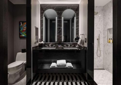 a bathroom with a sink and a toilet and a mirror at Daxton Hotel Birmingham, Curio Collection by Hilton in Birmingham