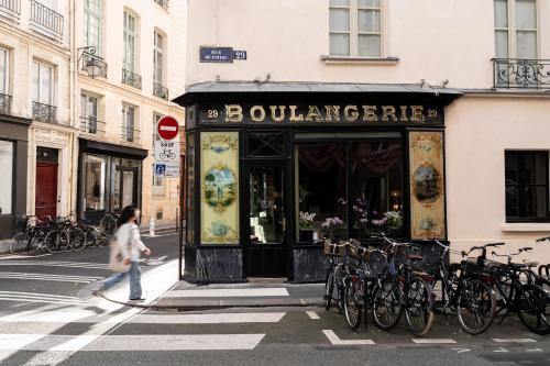 a woman walking past a building with bikes parked outside at Hôtel du Petit Moulin, Haute Couture hotel by Lacroix in Paris