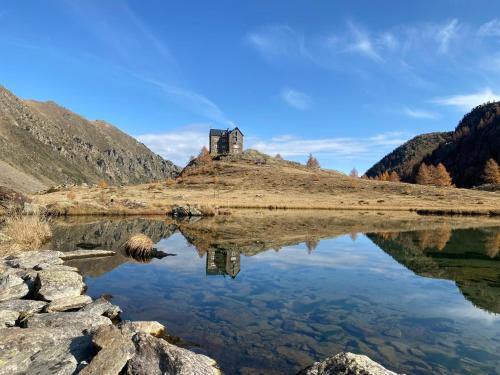 a reflection of a house in a lake in the mountains at Hotel Ristorante Ligure in Vinadio