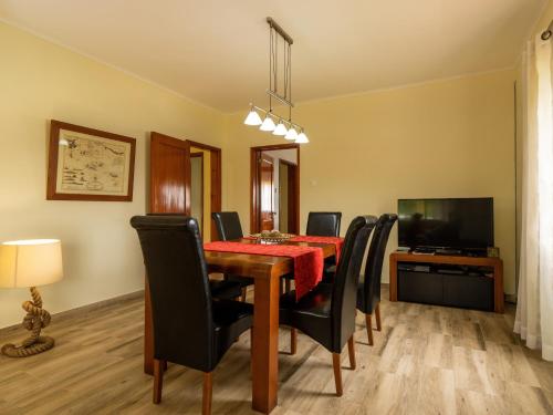 a dining room with a table and black chairs at Casa dos cinco sentidos in Feteira Pequena