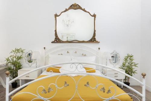a white bedroom with a yellow bed and a mirror at Morosoli Spa in Catania