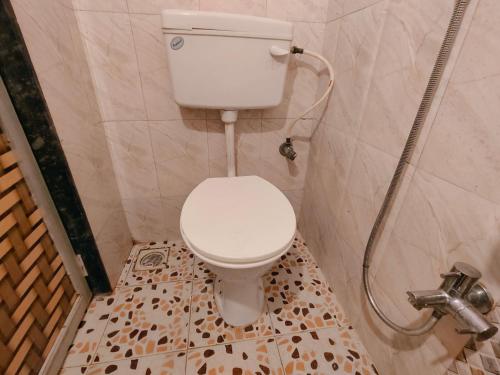a bathroom with a toilet and a shower at Satyam Guest House in Pune