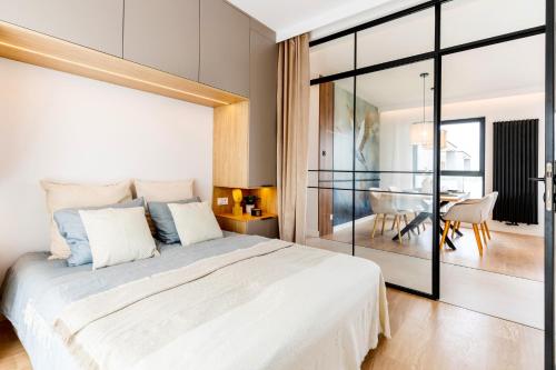a bedroom with a large white bed and a dining room at Marina Ostróda - 80 metrów luksusu z widokiem na jezioro in Ostróda