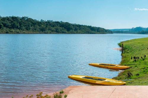 tres barcos amarillos sentados en la orilla de un lago en Quarto Casa de Campo Frente Lago, en Águas de Santa Bárbara