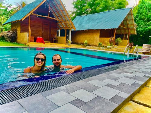 two people in a swimming pool next to a house at Udawalawa Safari House in Udawalawe