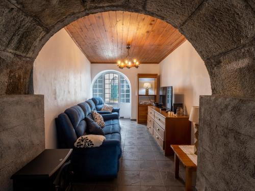 a living room with a blue couch and an archway at Casinha dos cinco sentidos in Nordestinho