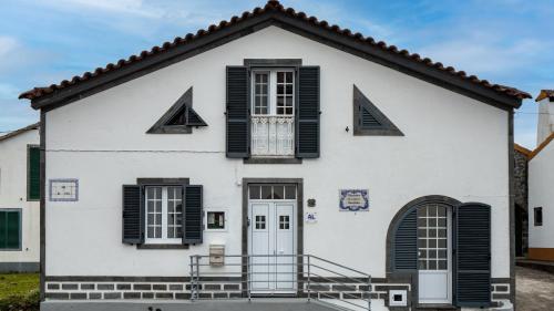 a white house with black shutters at Casinha dos cinco sentidos in Nordestinho