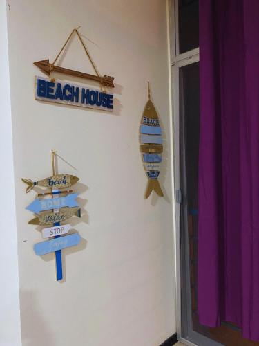 ein Strandhausschild und ein Surfbrett an einer Wand in der Unterkunft Condominio el sol in Salinas
