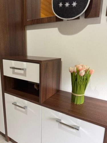 a vase of pink flowers sitting on a wooden shelf at Apartments Paradise in Ličko Petrovo Selo