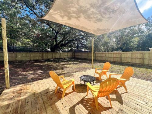 a patio with four chairs and a table and an umbrella at Palmetto Porch - Family Home Near Park Circle in Charleston