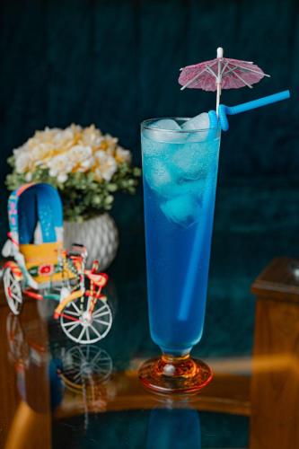 a blue drink with an umbrella on a table at Royal Raj Hotel in Rājshāhi