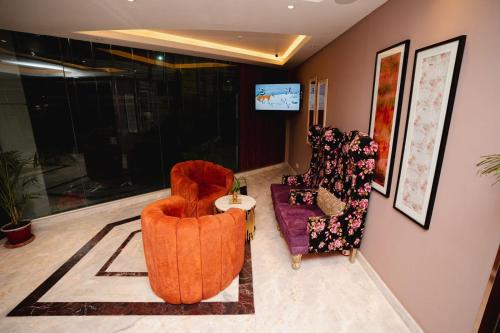 a living room with two chairs and a tv at Royal Raj Hotel in Rājshāhi
