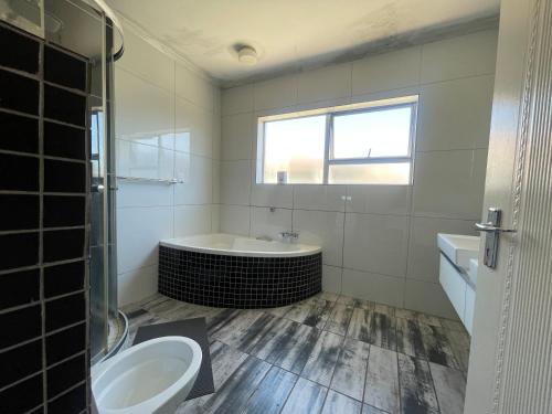 een badkamer met een bad, een toilet en een wastafel bij Zoe & Saint in Kaapstad