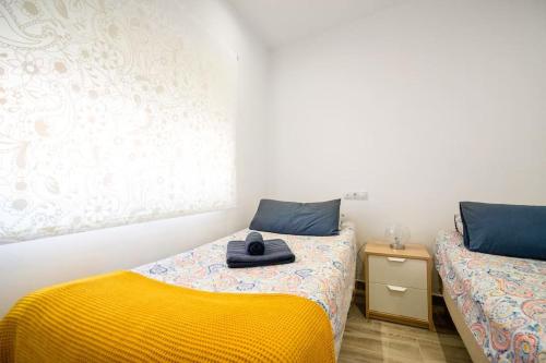 a bedroom with two beds and a yellow blanket at Piso a estrenar junto al mar ubicación inmejorable in Fuengirola