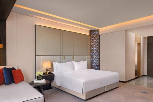 a bedroom with a large white bed and a couch at Amari Colombo, Sri Lanka in Colombo