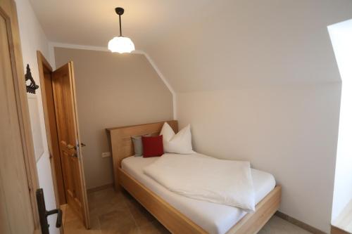a small bedroom with a bed with white sheets and red pillows at Mala Taverna in Kalwang