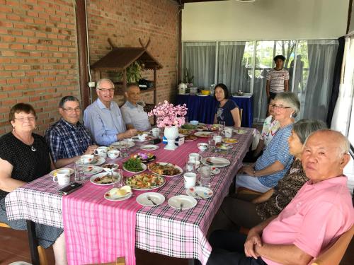 a group of people sitting around a table with food at Sripiamsuk Resort Bangkok in Pathum Thani