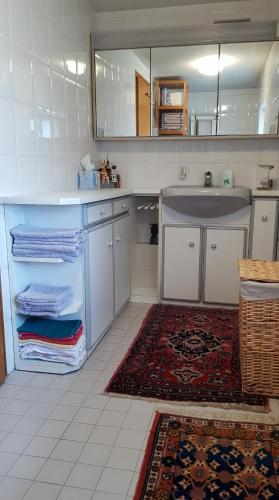 a kitchen with white cabinets and a sink and a rug at Unser Woidhaisl - idyllisches Ferienhaus im Bayerischen Wald in Neukirchen
