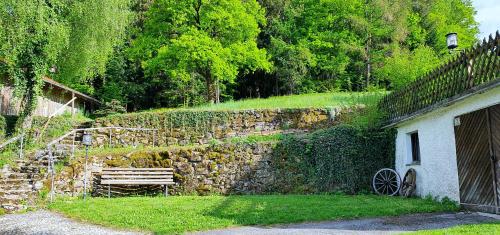 a stone wall with a bench next to a building at Unser Woidhaisl - idyllisches Ferienhaus im Bayerischen Wald in Neukirchen