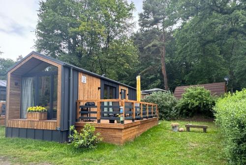 a small cabin with a large deck in the grass at Tiny House Lotta - Auszeit-Oase am Plauer See in Stuer