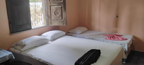 a group of three beds in a room with a window at Pousada Sossego do Mailson in Barreirinhas