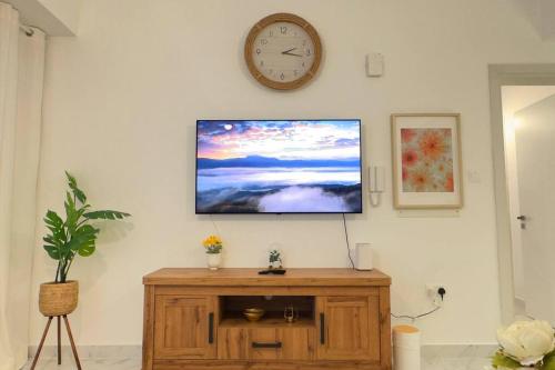 a tv on a wall with a clock on the wall at Daisy 1BR Oasis - Elegant Urban Escape in Abu Dhabi