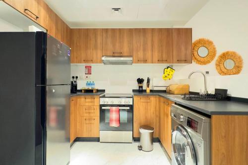 a kitchen with wooden cabinets and a stainless steel refrigerator at Daisy 1BR Oasis - Elegant Urban Escape in Abu Dhabi