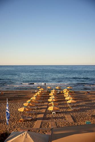 a group of umbrellas and chairs on a beach at Vlachakis Hotel in Stalida