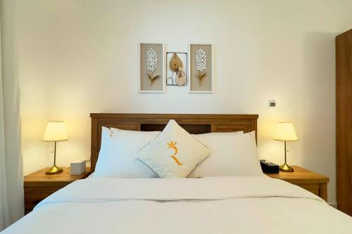 a bedroom with a white bed with three pictures on the wall at Daisy 1BR Oasis - Elegant Urban Escape in Abu Dhabi