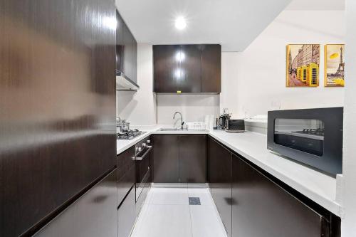 a kitchen with a sink and a microwave at 1BR Dubai, Merano Canal View Retreat Near Metro Dining Shopping Mall in Dubai