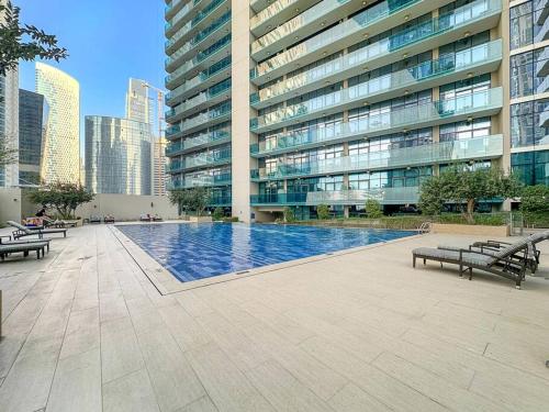 a large building with a swimming pool in a city at 1BR Dubai, Merano Canal View Retreat Near Metro Dining Shopping Mall in Dubai