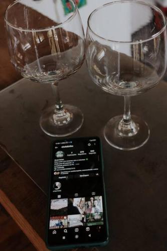two wine glasses and a cell phone on a table at Chalé Biribó in Conceição do Mato Dentro