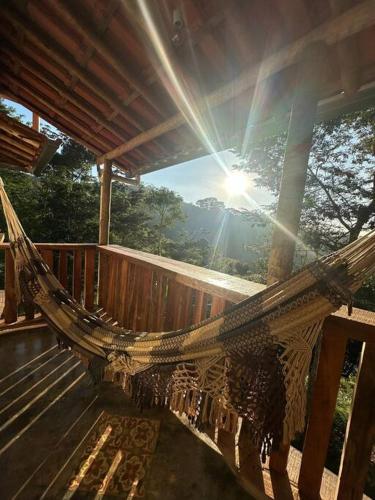 a hammock on a deck with the sun in the background at Chalé Biribó in Conceição do Mato Dentro