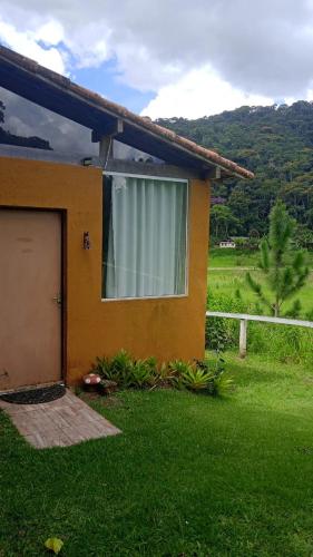 a house with a window and a door in the grass at Pousada Jupter in Teresópolis