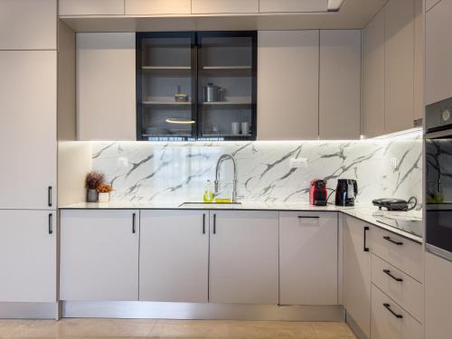 a kitchen with white cabinets and marble counter tops at VILLA 8 By ProLiving Hospitality in Thessaloniki