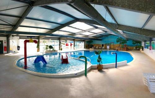 a large swimming pool with a person in the water at La Palmyre - Les Mathes - Mobil home 3 ch LUXUEUX de 40m2 - Grand emplacement dans village loisirs 4 étoiles - "les Charmettes 394" proche FUN ZONE in Les Mathes