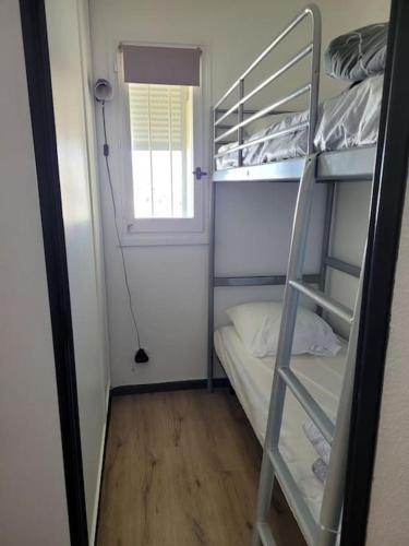 Cette petite chambre comprend des lits superposés et une fenêtre. dans l'établissement Appartement en résidence avec vue et accès au port, à Gruissan